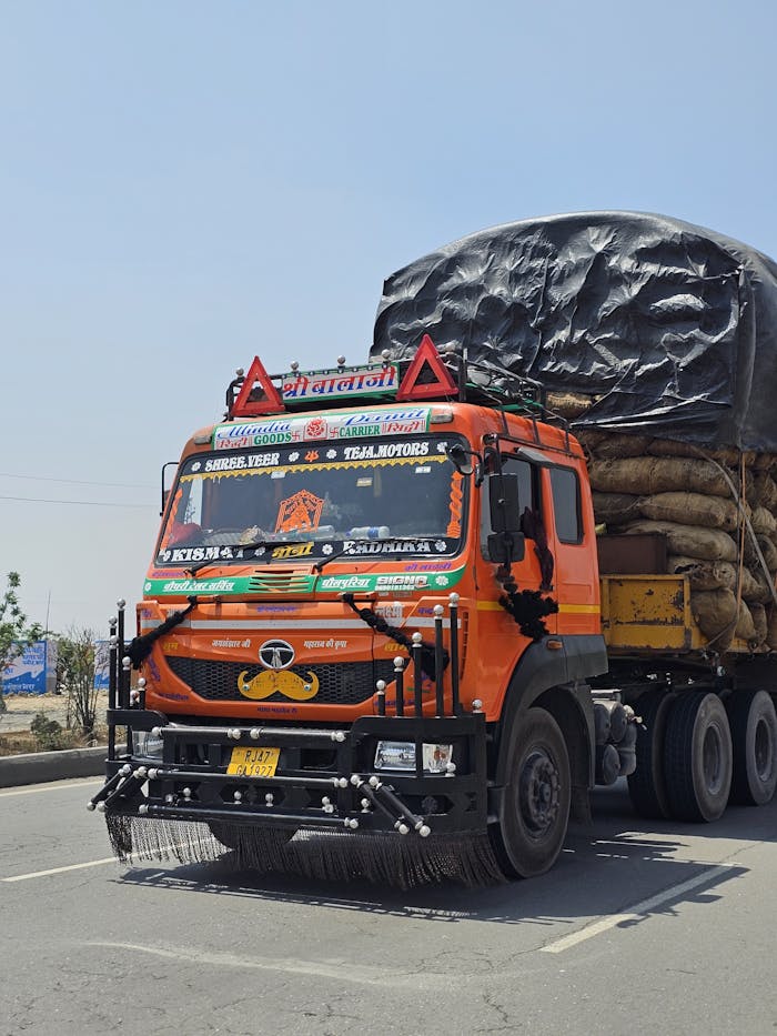 Colorful Indian cargo truck loaded with goods on highway, showcasing vibrant cultural decorations.